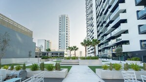 A modern urban courtyard with seating areas, planters, and tall buildings in the background.