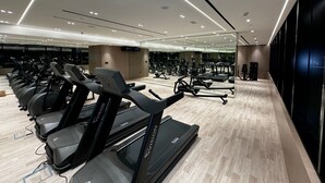 A modern gym with multiple treadmills, exercise bikes, and a large mirror reflecting the space.
