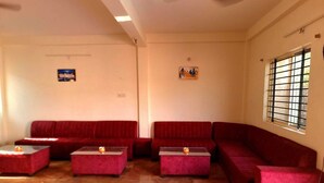 A living room with a red sofa set, a coffee table, and a window with bars. - Arika Farm House (Indore)