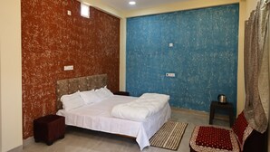 A bedroom with a bed, a ceiling fan, a small table, and a rug. - Arika Farm House (Indore)