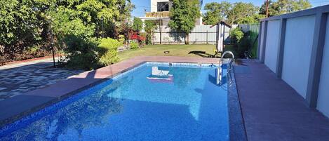 A rectangular swimming pool with a tiled edge, surrounded by a concrete deck.