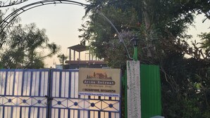 A gated entrance with a sign for Arika Retreat, a farmhouse stay, including contact details and location. - Arika Farm House (Indore)
