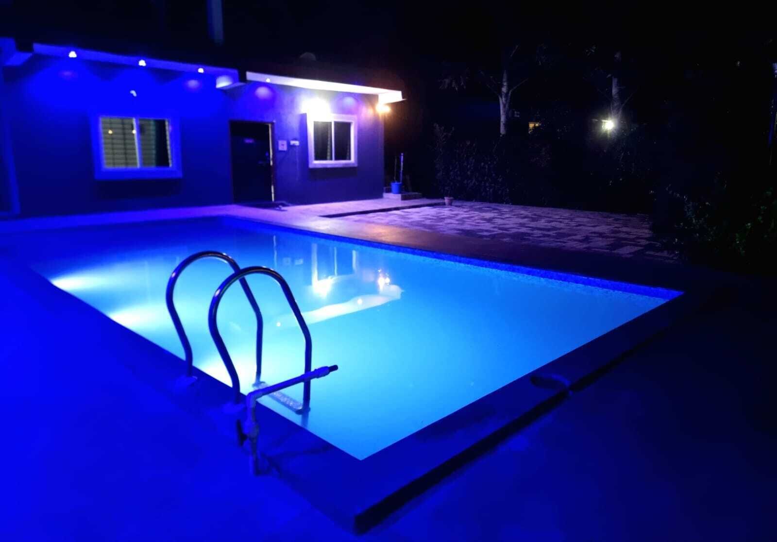A swimming pool with a blue light, a door, and a window.
