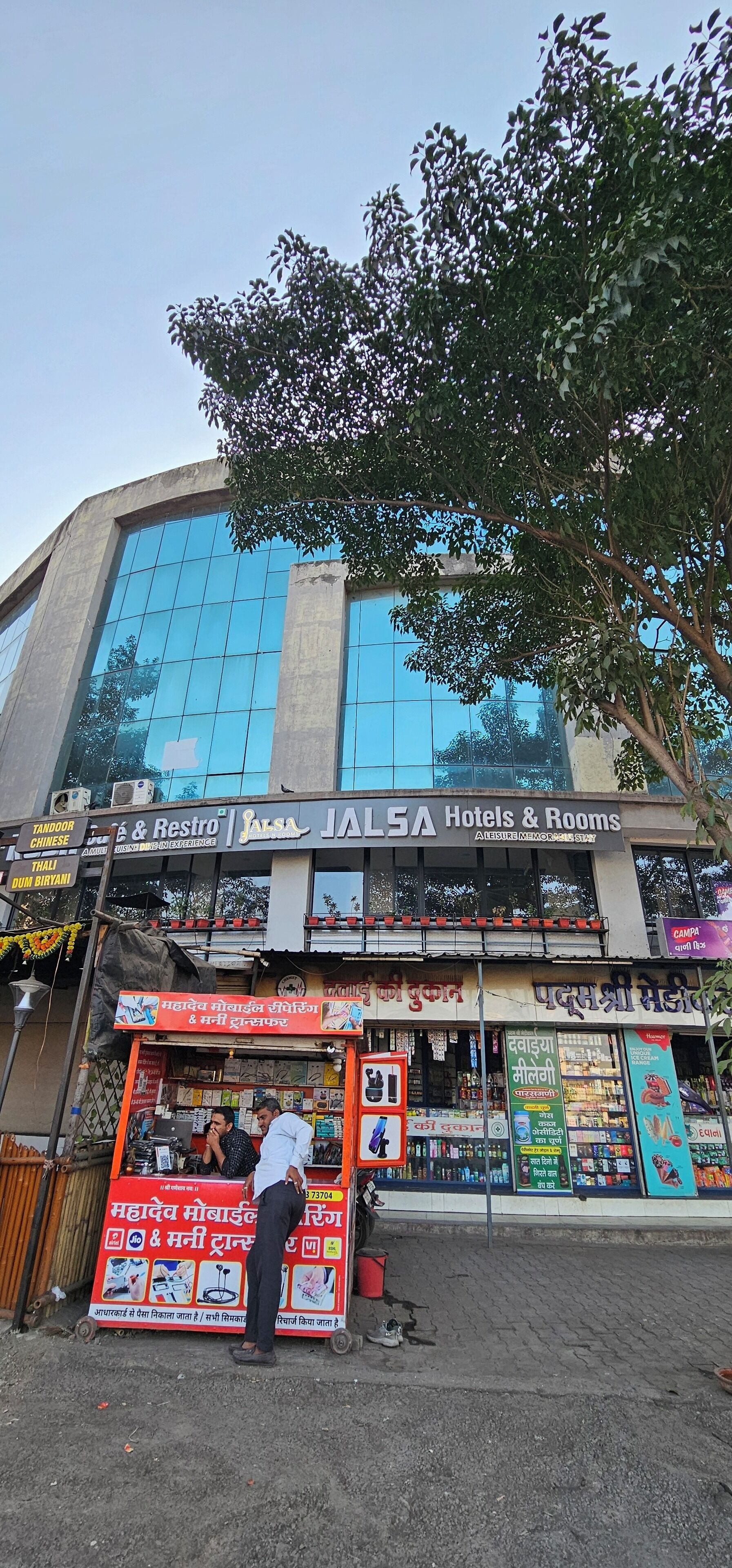 Un hôtel doté d’une grande façade en verre, de nombreux panneaux indicateurs dans différentes langues et d’un petit kiosque à l’avant.