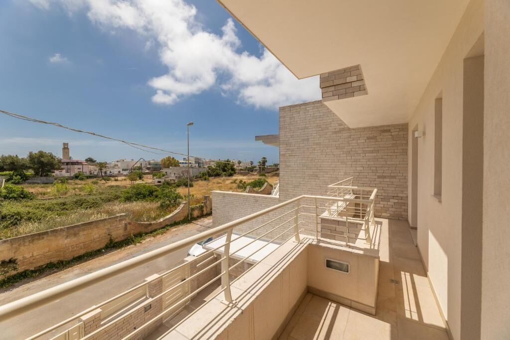 A residential building with a balcony, a staircase, and a view of the surrounding area.