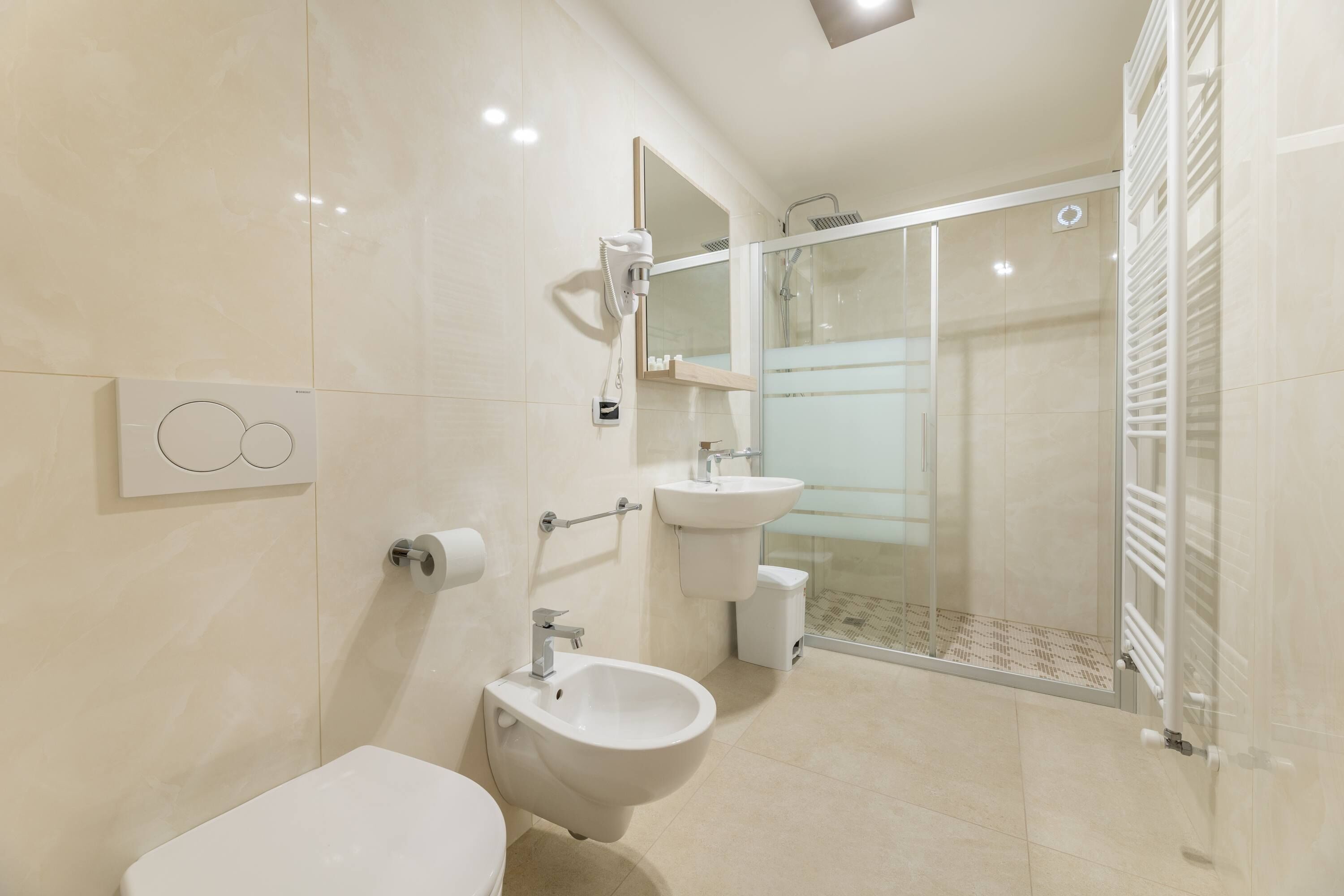 Un baño moderno con bidé, inodoro, lavabo y cabina de ducha de cristal.