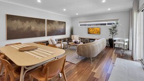 Una sala de estar moderna con una mesa de comedor de madera, asientos cómodos y grandes cuadros abstractos.