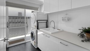 Una cocina moderna con lavadora y secadora integradas, un fregadero y una cesta en la encimera.