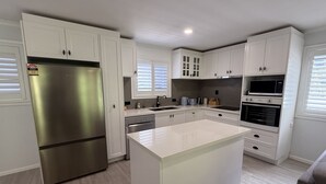 Una cocina moderna con armarios blancos, electrodomésticos de acero inoxidable y una isla central.
