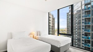 Una habitación de hotel con dos camas, un ventanal grande y vistas a un edificio alto.