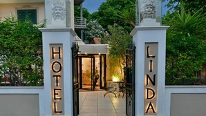 Der Eingang eines Hotels mit beleuchteter Beschilderung und einem kleinen Tisch mit Stühlen vor der Tür.