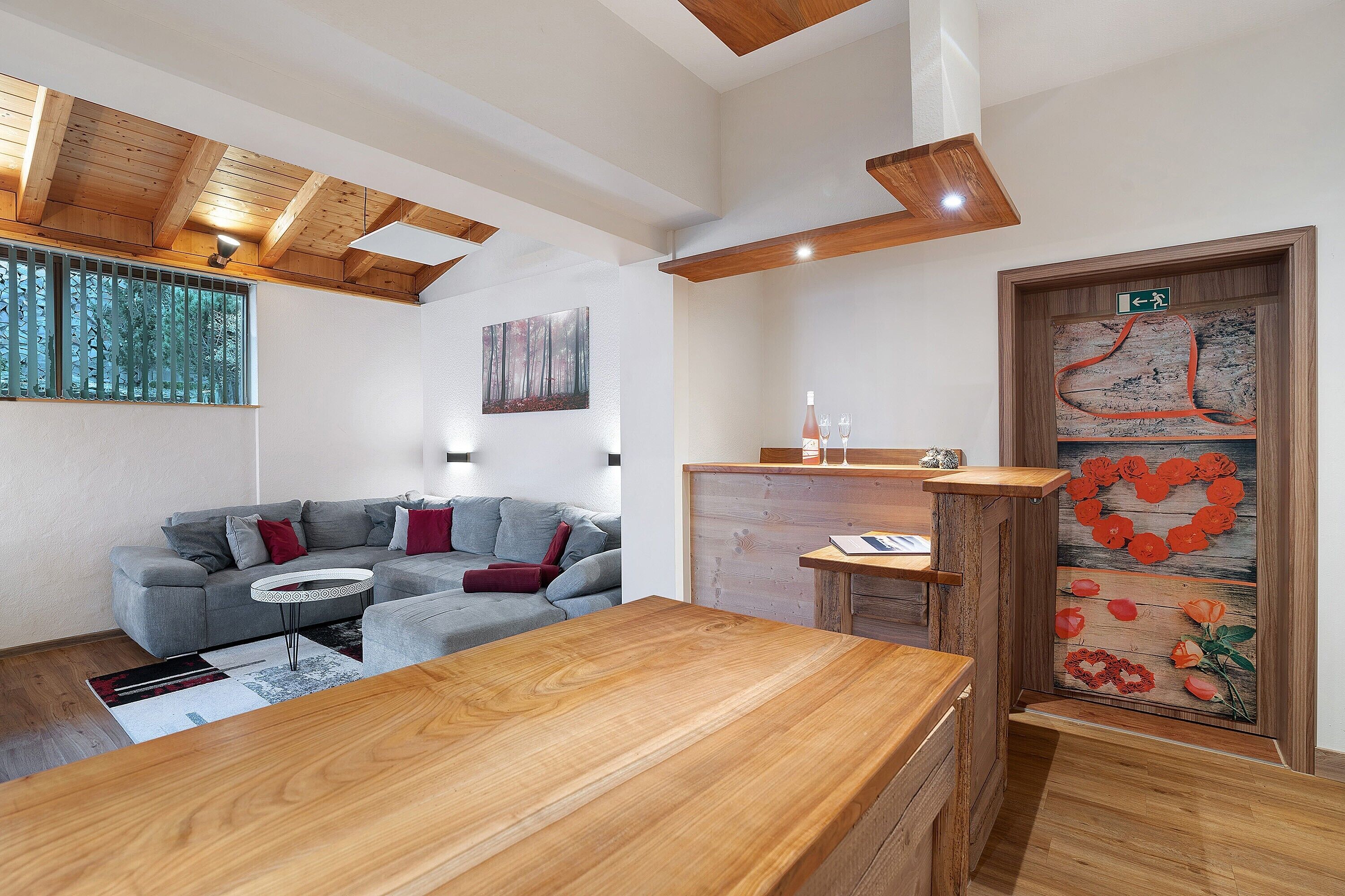 Ein modernes Wohnzimmer mit einem Holzesstisch, einem grauen Sofa und einem Bild an der Wand.