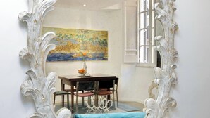 A dining area with a table, chairs, and a painting on the wall. - Amazing Apartment by the Pantheon (Rome)
