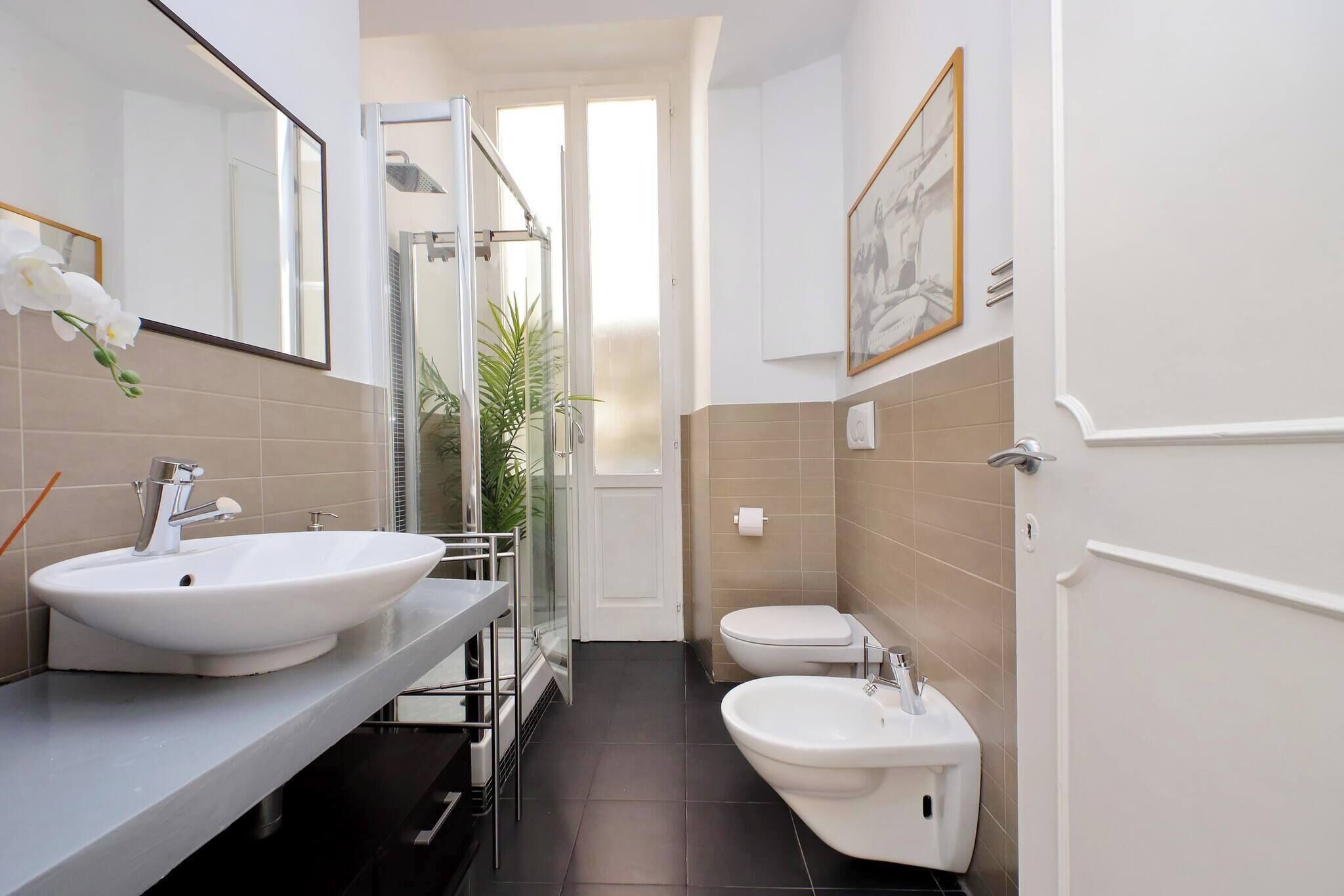 Une salle de bain moderne avec un grand miroir, deux lavabos, des toilettes et une douche.