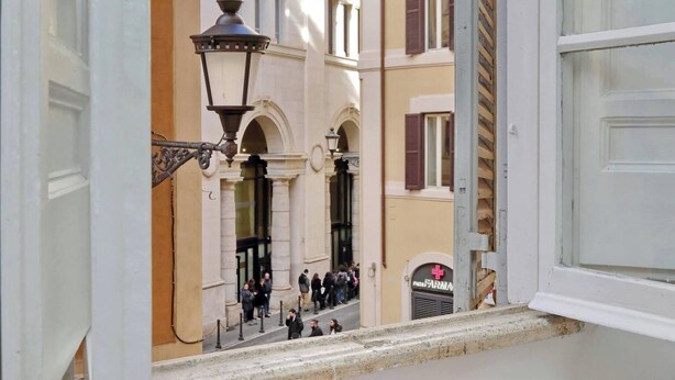 A street view with a pharmacy sign, a lamp post, and people walking. - Amazing Apartment by the Pantheon (Rome)