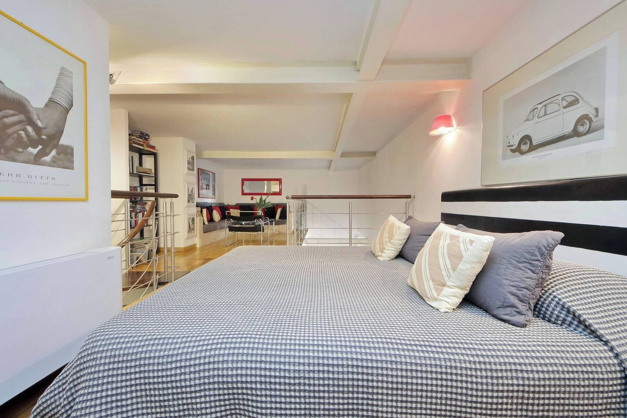 Ein Schlafzimmer mit kariertem Bettbezug, schwarzem Kopfteil und einer roten Lampe.