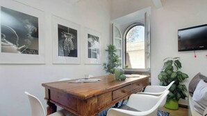 Ein Essbereich mit einem Holztisch, weißen Stühlen und gerahmten Bildern an der Wand.