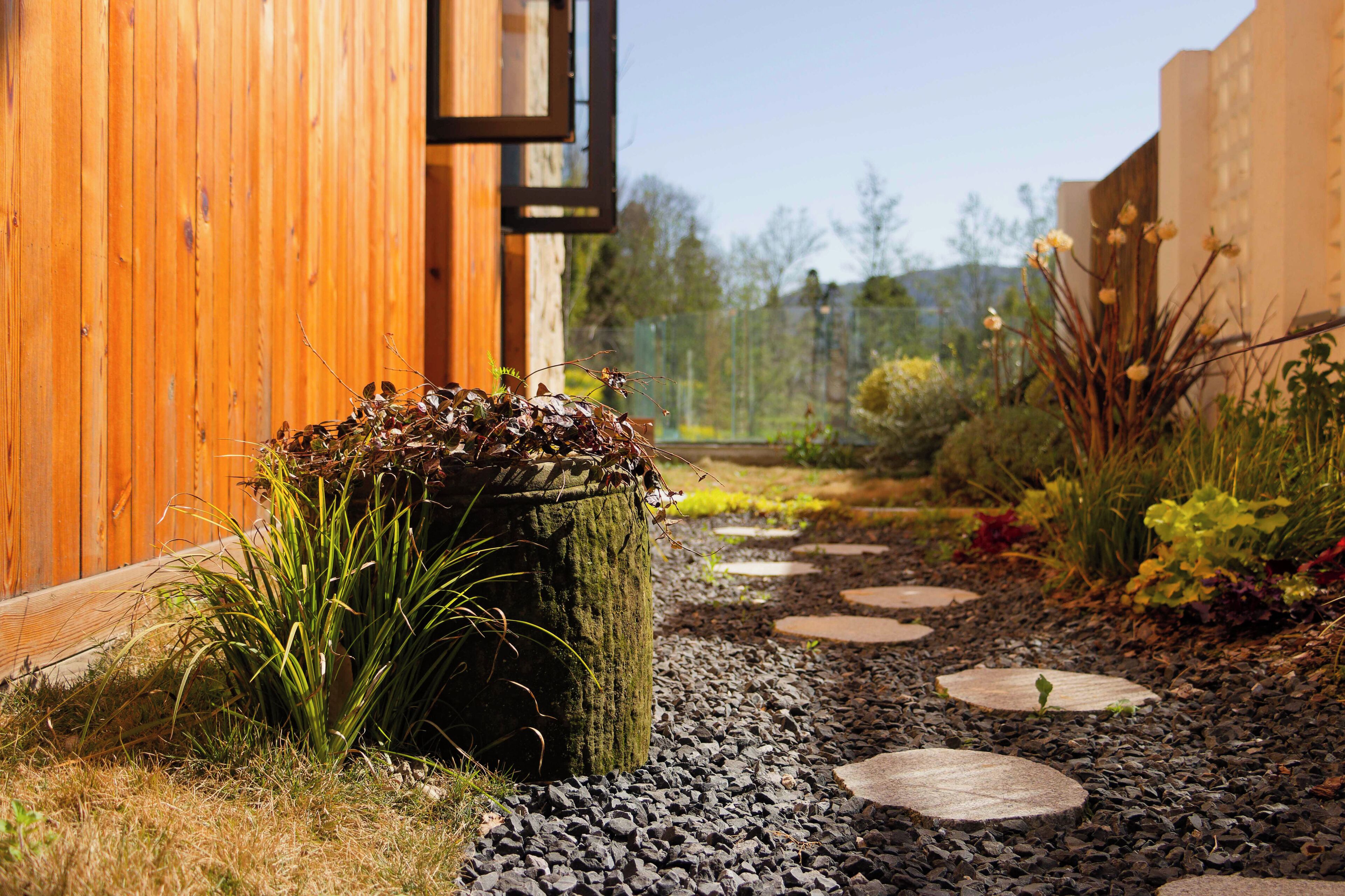 A garden pathway with stepping stones leading to a wooden building.