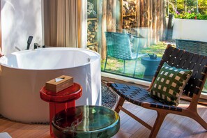 Un baño moderno con una bañera blanca grande, un taburete rojo y un cuenco de vidrio.