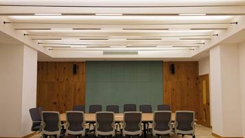 Une salle de conférence dotée d’une longue table et de chaises, de murs recouverts de panneaux en bois et d’un éclairage moderne.