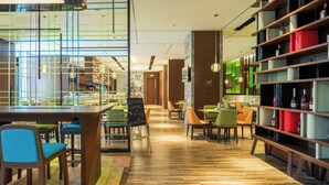 A modern restaurant interior with wooden furniture, a glass partition, and a variety of seating arrangements. - Hampton by Hilton Hangzhou Binjiang (Hangzhou)