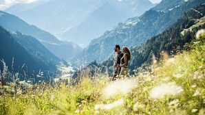 A couple hiking on a mountain trail with a view of distant mountains.