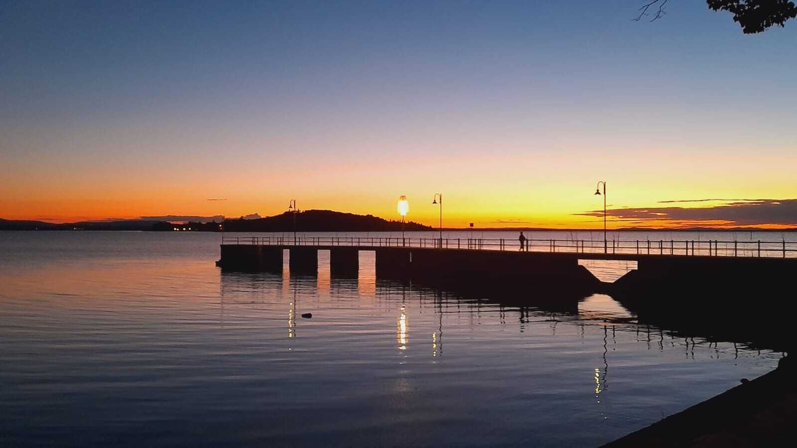 Un muelle se adentra en aguas tranquilas al atardecer, bajo un cielo despejado.