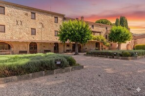 A courtyard with stone buildings, a gravel path, and well-maintained hedges. - OASIS THE PEARL APARTMENT - NATURAL POOL AND GYM (Passignano sul Trasimeno)