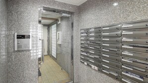 En hall med ett klinkergolv, en metallpostinkast och en glasdörr som leder till ett annat rum.