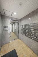 A hallway with a mail slot, a no posting sign, and a mail drop area.