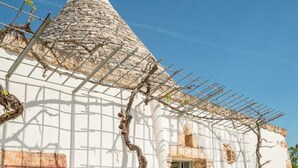 Ein traditionelles Gebäude mit einem kegelförmigen Dach, steinernen Bögen und einer großen Vase.