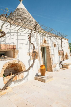 A traditional building with a conical roof, stone arches, and a large vase. - Luxury Trullo with Private Pool near Ostuni – Itria Valley (Ostuni)