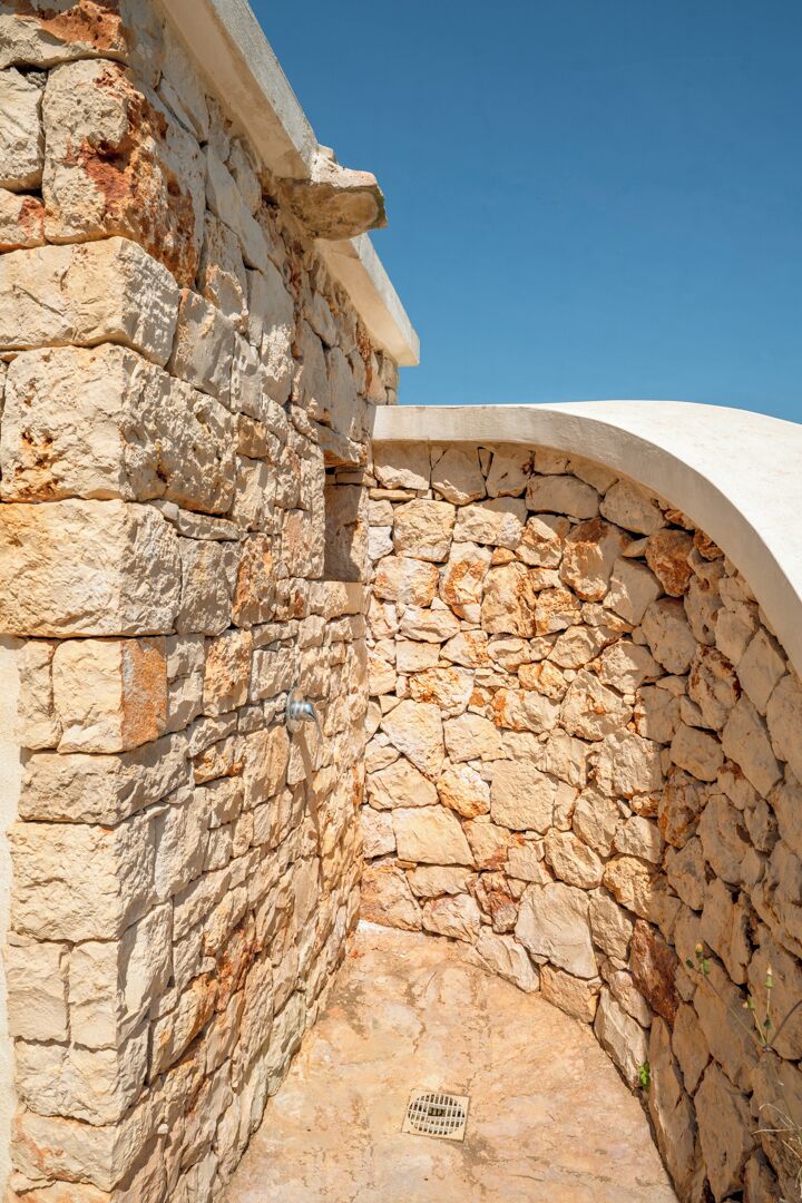 A stone wall with a drainpipe and a curved white structure.
