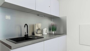 Et moderne køkken med en sort vask, en hvid kaffemaskine og en potteplante.