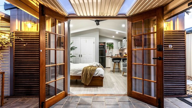 Quarto de hotel moderno com uma cama grande, uma escrivaninha e uma cozinha compacta.