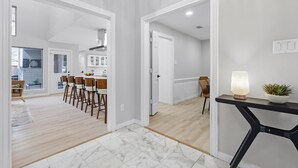 Un interior moderno con comedor, cocina y un pasillo que conduce a otra habitación.