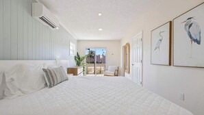 A bedroom with a large bed, a chair, and a view of the outside. - Welcome to The Drift Your Laid-back Beach Escape in Cocoa Beach! 2/2 (Cocoa Beach)