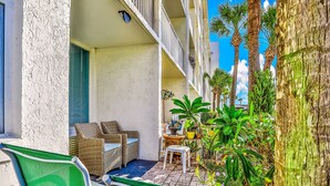 A balcony with wicker furniture, a small table, and potted plants. - Ocean Jewels Club 104 - Beach Jewel (Daytona Beach)