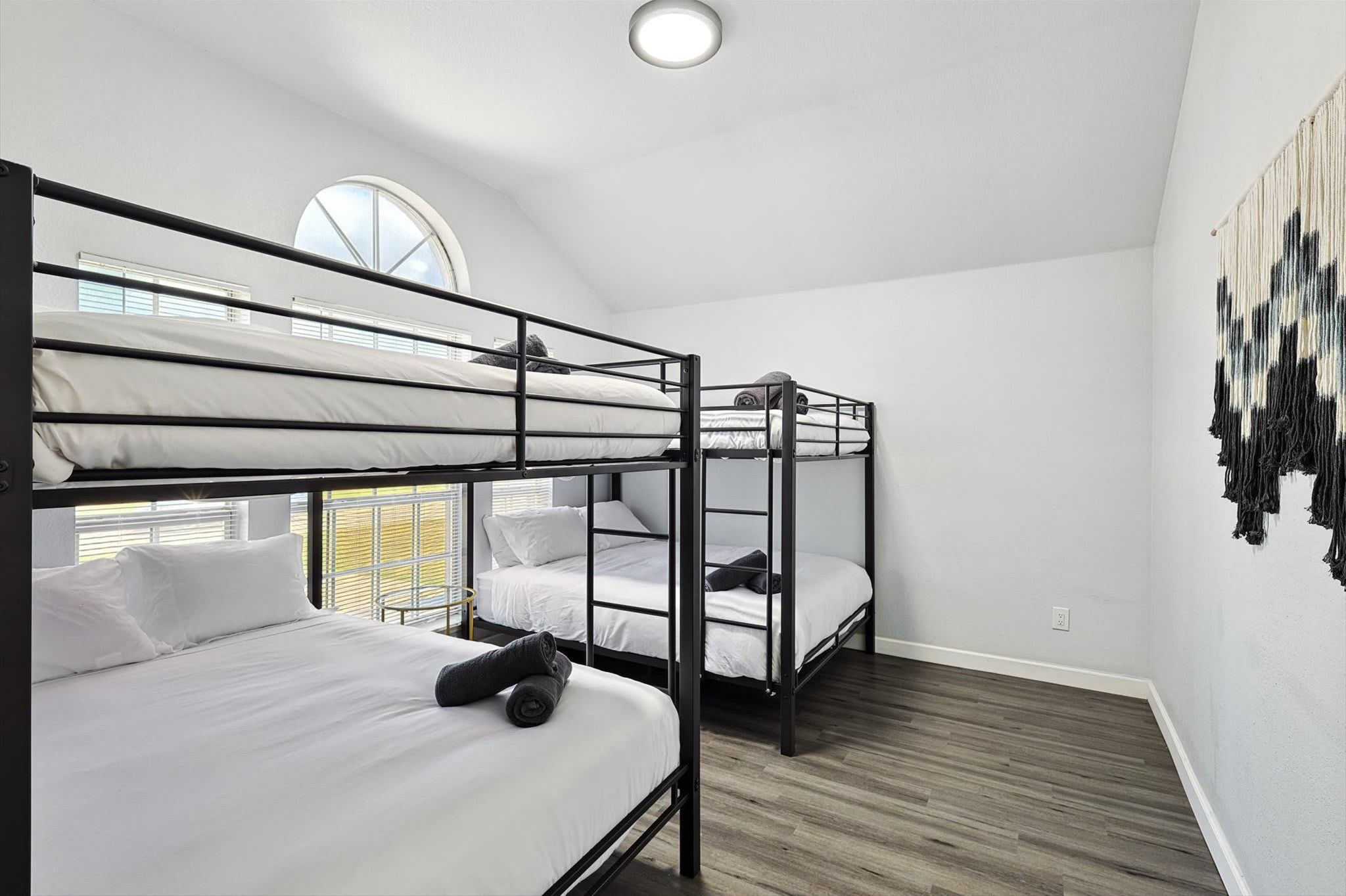 A bunk bed room with a skylight, a wall art piece, and a wooden floor.
