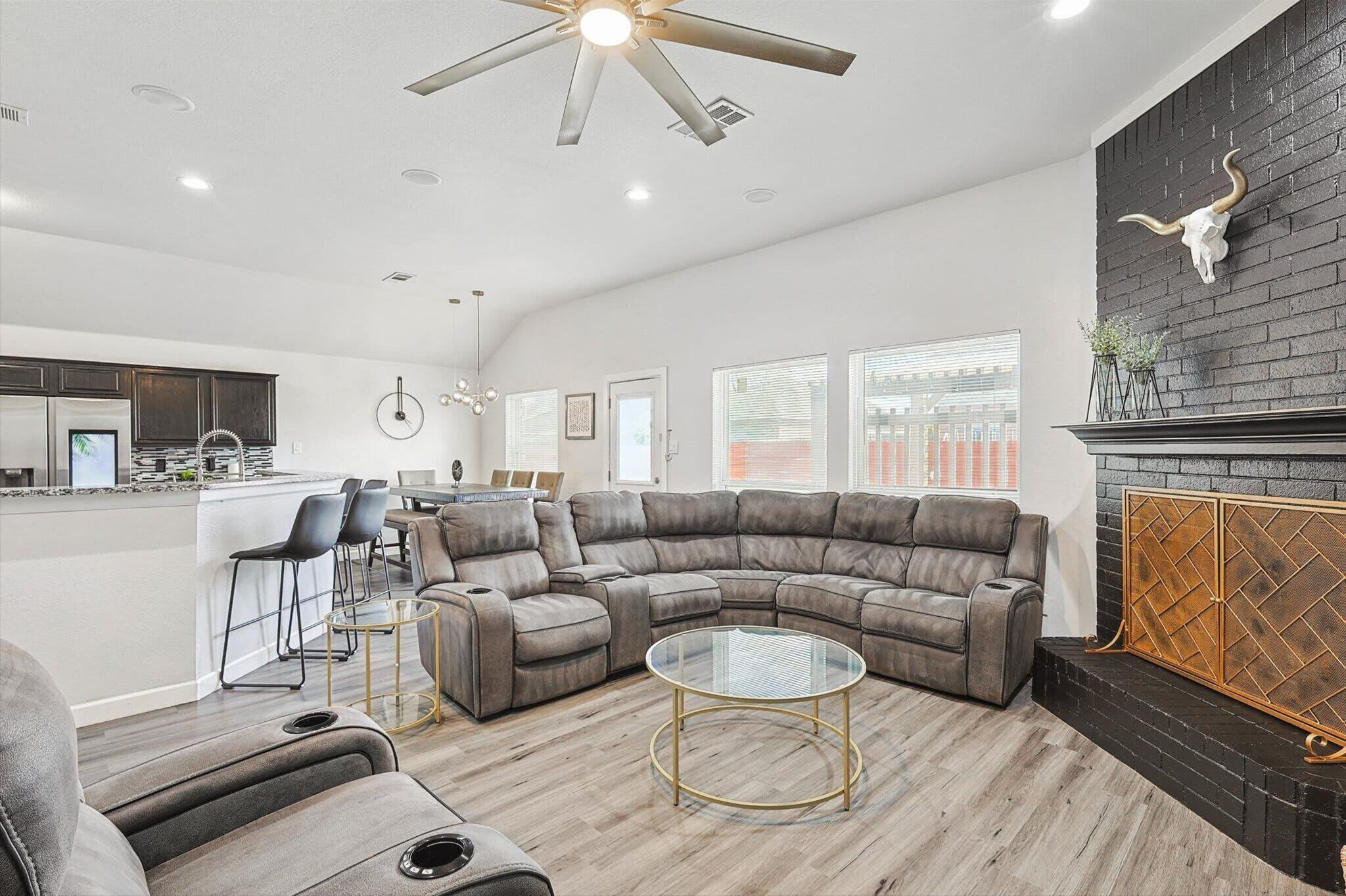 A modern living room with a sectional sofa, a glass coffee table, and a fireplace with a decorative metal screen.