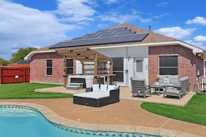 A house with a backyard patio, a swimming pool, and solar panels on the roof. - 5BR Getaway in Desoto With Pool, Hot Tub & Cinema (DeSoto)
