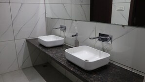 Ein Badezimmer mit zwei weißen Waschbecken, einer Granit-Arbeitsplatte und einer Marmor-Spritzschutzwand.