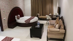 Ein modernes Hotelzimmer mit einem gebogenen Bett, einer Couch, einem Couchtisch und einem Fernseher.
