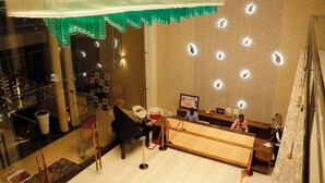 Ein Hotel-Empfangsbereich mit Glastrennwand, einer Rezeption und einer Sitzecke mit Stühlen.
