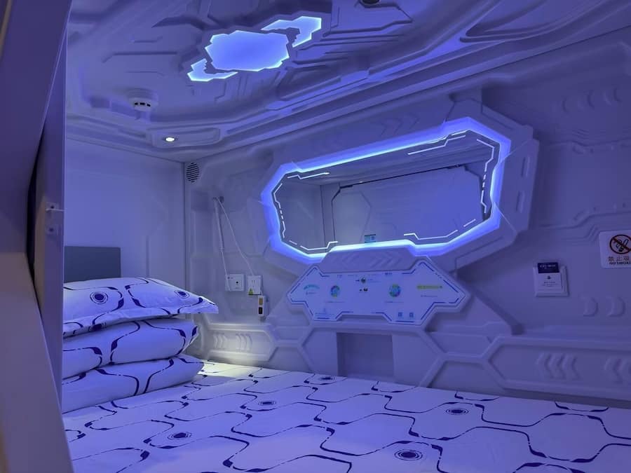 Una habitación futurista con una cama, paneles de control y un cartel de prohibido fumar.