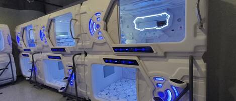 A row of futuristic massage chairs with illuminated blue accents and control panels.