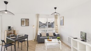 Ett modernt vardagsrum med en matplats, en soffa, ett soffbord och en tv.