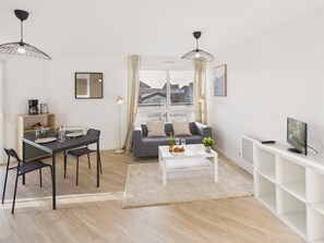 A modern living room with a dining area, a sofa, a coffee table, and a TV. - Close to city center – Apartment for 2 with balcony (Pont-l´Abbé)