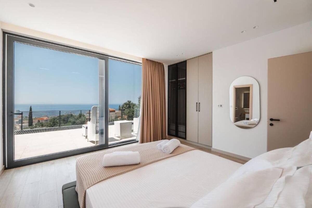 A hotel room with a large sliding glass door leading to a balcony with a view of the sea.