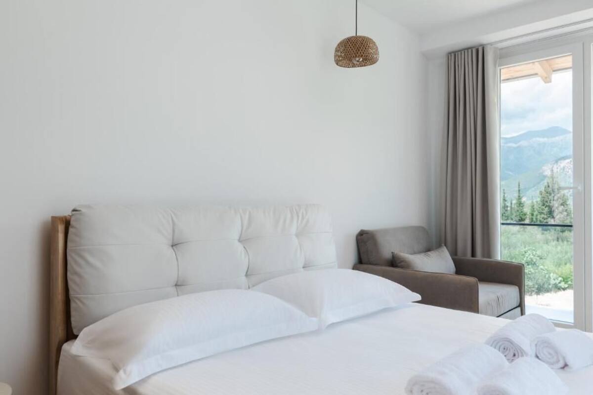A hotel room with a large bed, a chair, and a view of the outdoors.